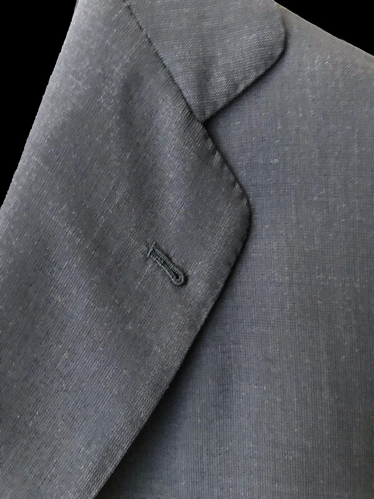 Detalle de solapa de chaqueta gris con ojal